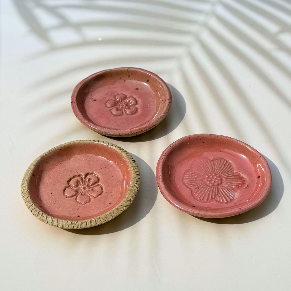 Three pink ceramic dishes with floral designs on a light background